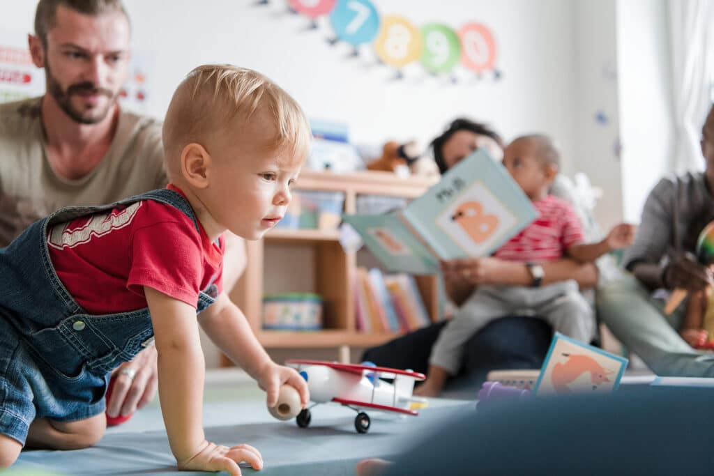 Little boy playing with toy airplane in a classroom