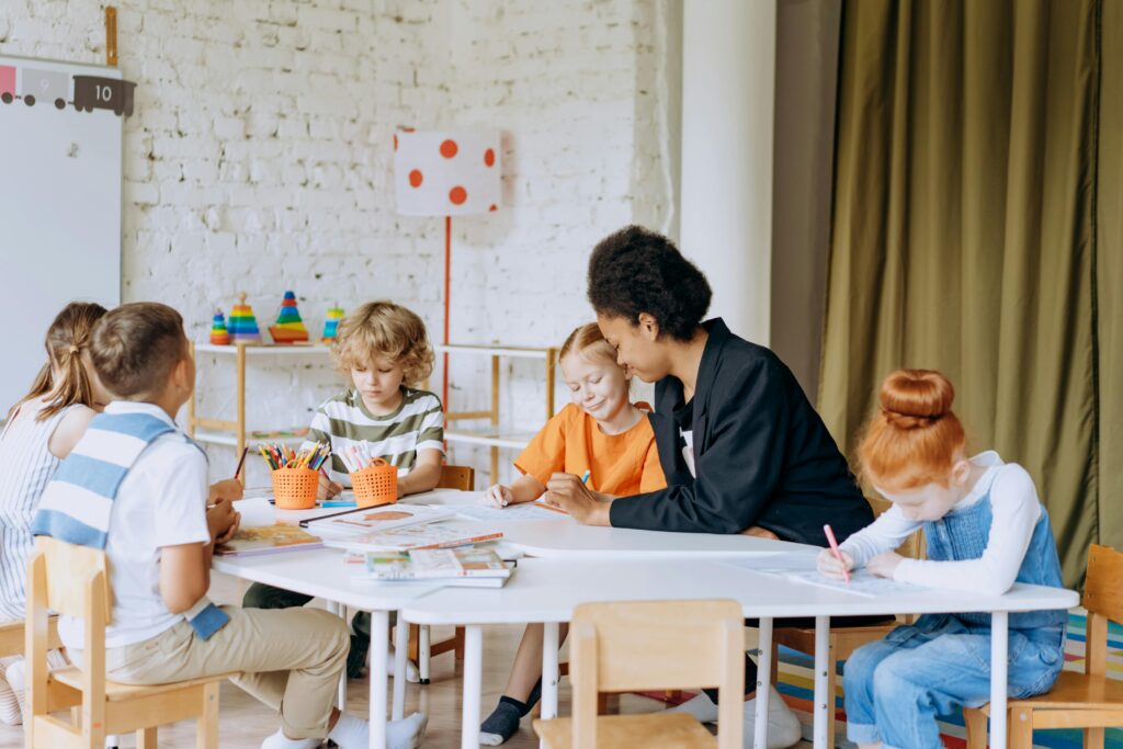 Children sitting around a classroom table engaging in a learning activity, promoting collaboration and child Health in education.