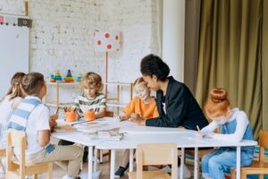 Children sitting around a classroom table engaging in a learning activity, promoting collaboration and child Health in education.