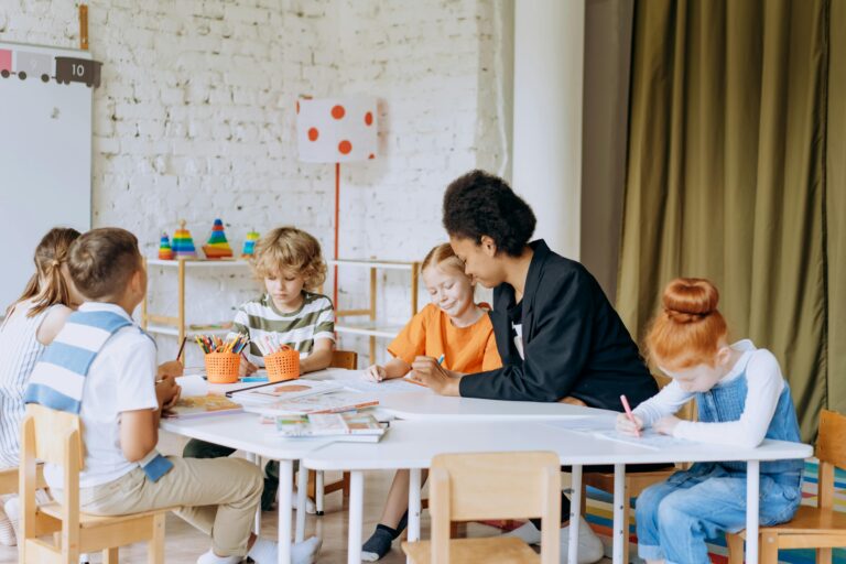 Children sitting around a classroom table engaging in a learning activity, promoting collaboration and child Health in education.